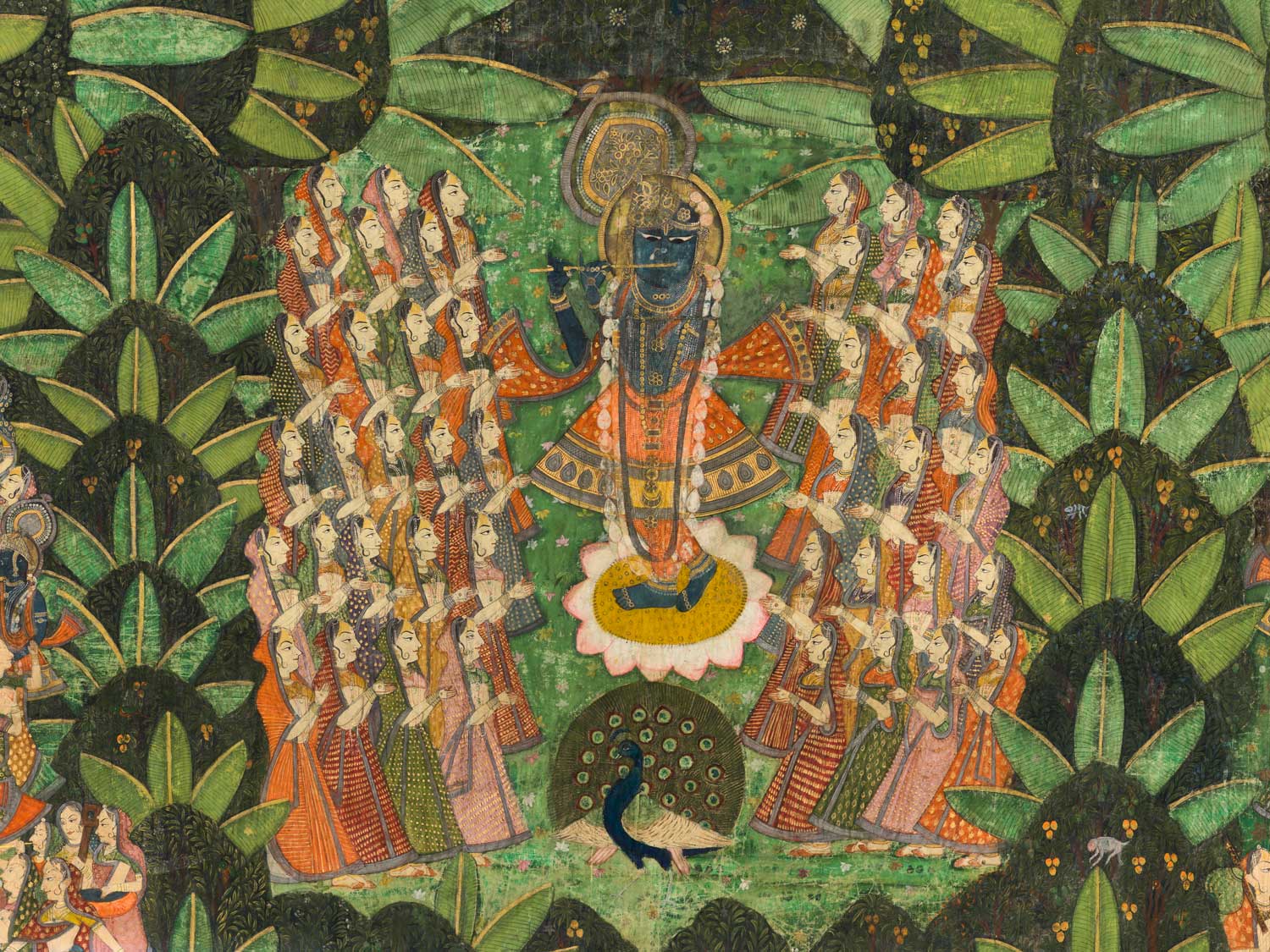 In a green grove, a man with blue skin plays a flute. He has a halo and wears a peacock feather crown. Women in colorful garments surround him. A peacock spreads its wings in front of him.