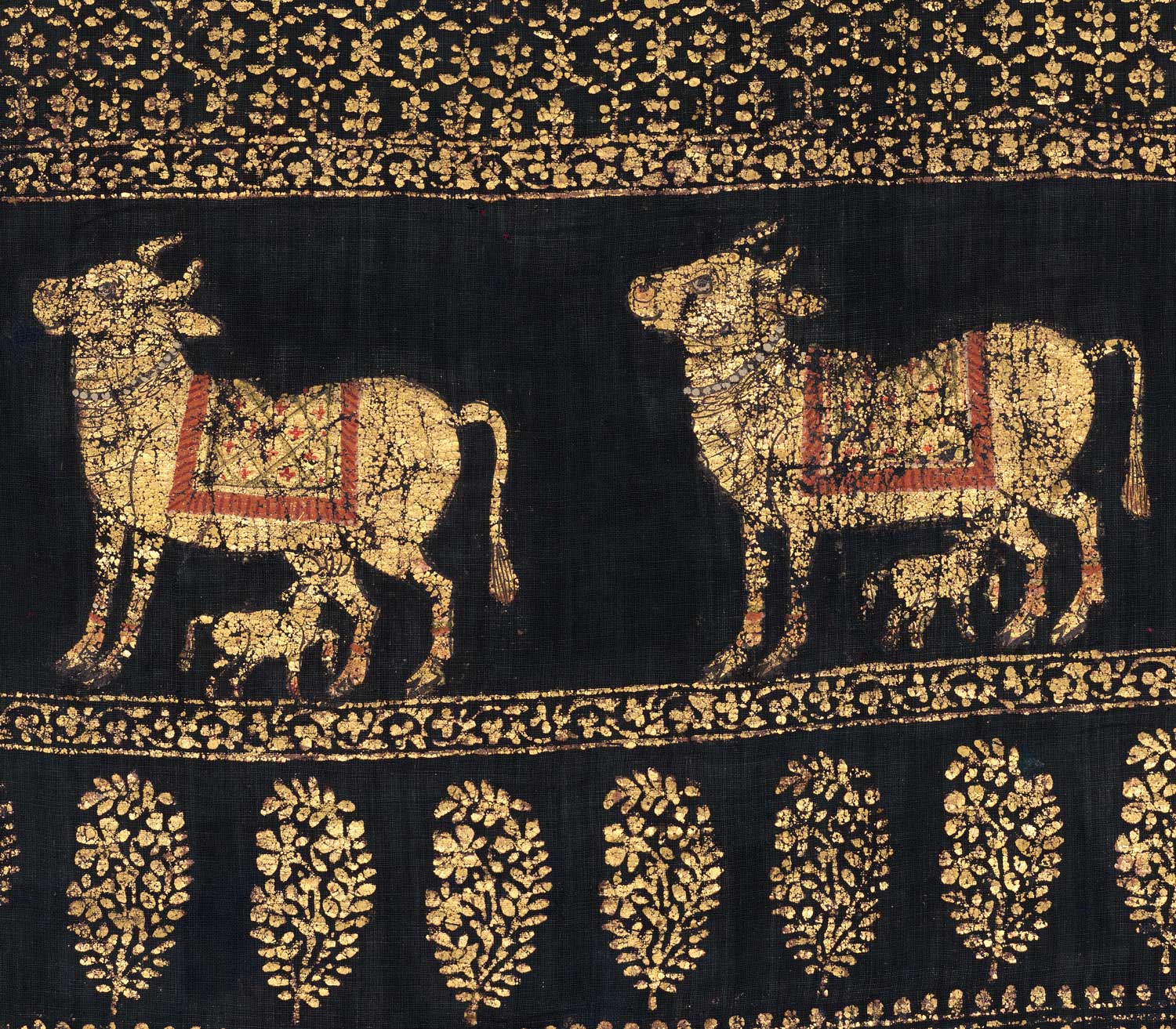 Two gold cows look up to the left, each with a calf feeding at their udders. Floral patterns run horizontally above and below.