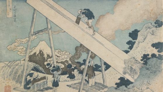 The sacred mountain appears in the distance, framed by the 'A' support securing a large timber as two carpenters saw planks and another sharpens his saw under a straw lean-to.