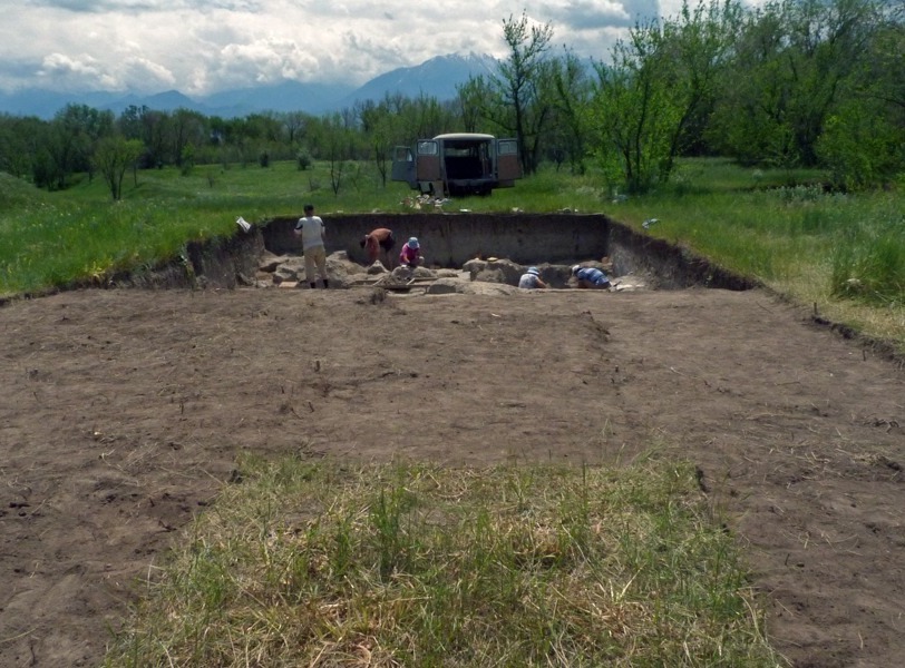 People digging in large square hole.