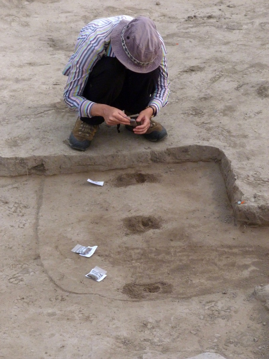 A person wearing a hat crouched down with small tools in their hands.