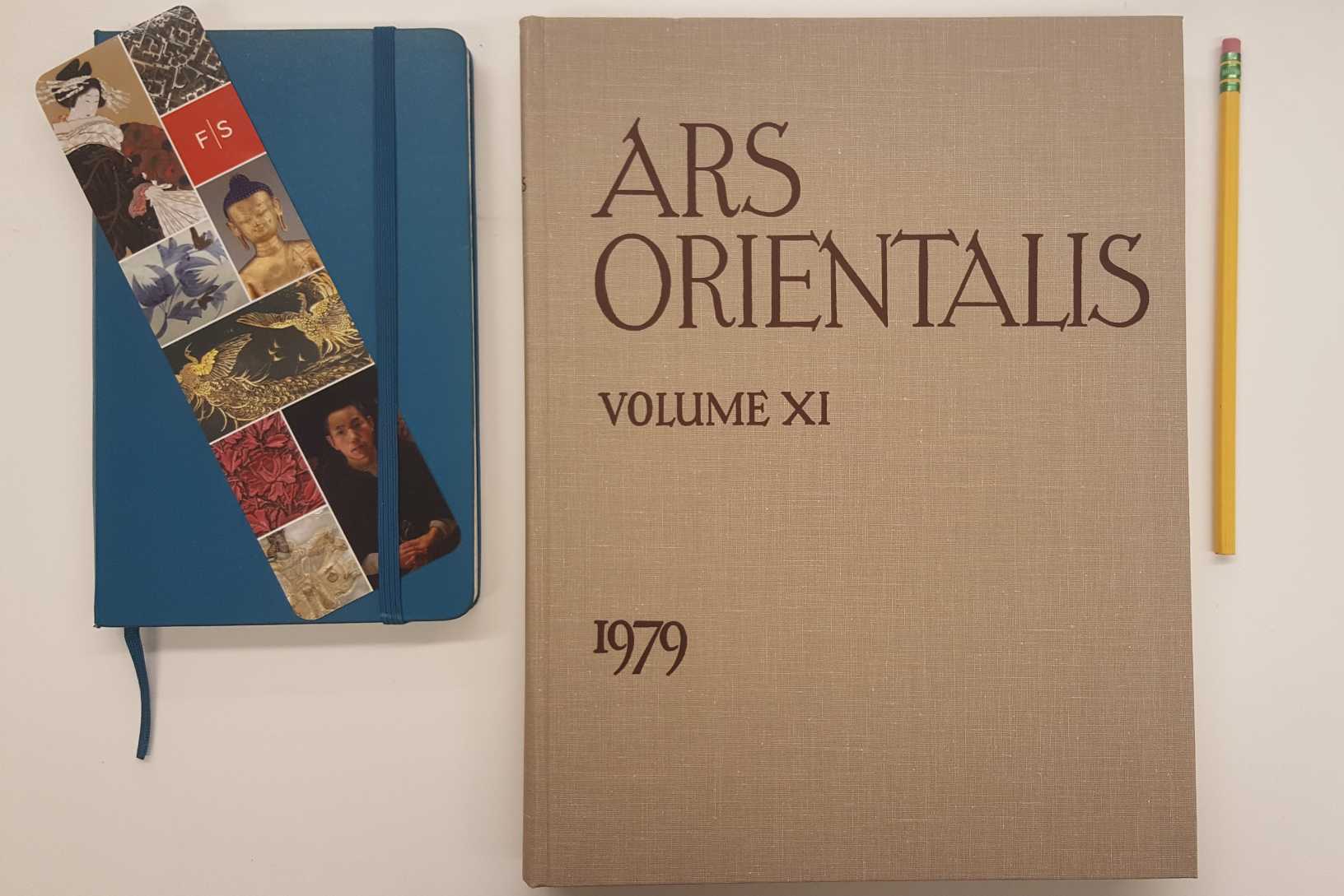 From left to right, a blue journal with a Freer Sackler bookmark, the 11th volume of Ars Orientalis, and an unsharpened yellow pencil.