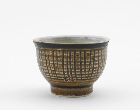 Side view of short rounded wine cup vessel decorated with vertical lines.