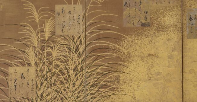 A gold-and-black screen with wispily painted reeds, staggered blocks of Japanese calligraphy, and a brushed, speckled gold texture.