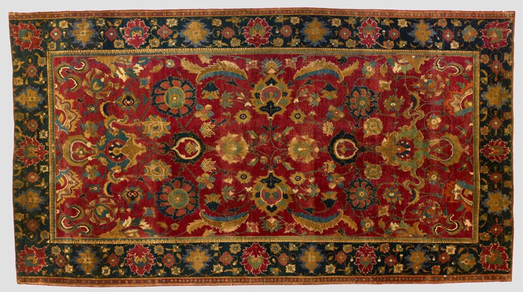 A red carpet with a dark border and intricate floral patterning.