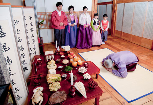 a family in traditional korean clothing and a table full of food, candles and incense