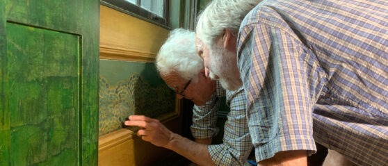 two conservators look closely at a panel in the Peacock Room