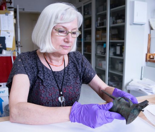 a conservator handles an ancient bronze object