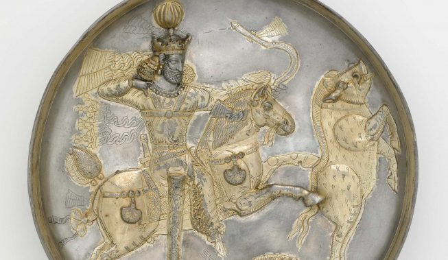 A shallow silver dish with gold relief decoration featuring a man on horseback drawing a bow