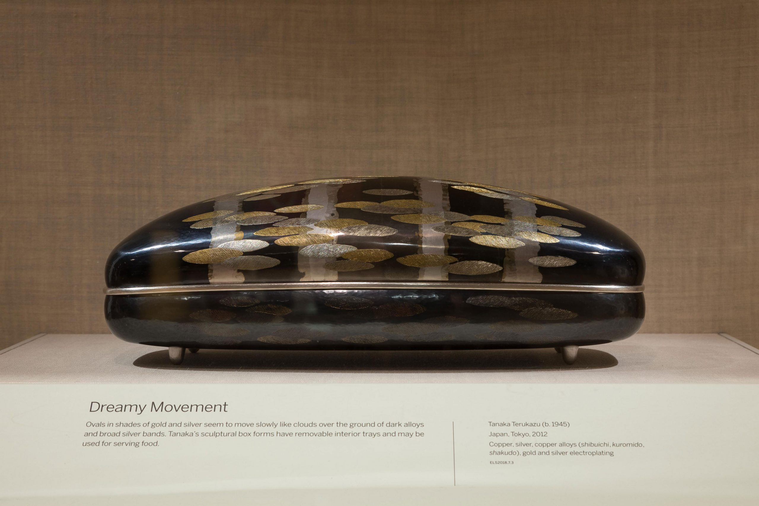 dark rectangular metal box with gold, oval markings and silver strikes.