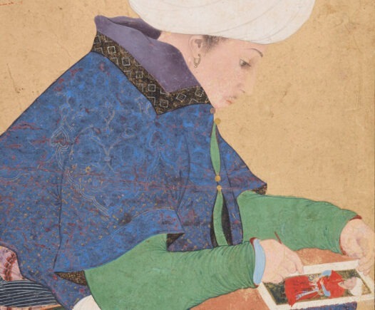 painting of a man in a turban working on a painting or drawing in his lap.