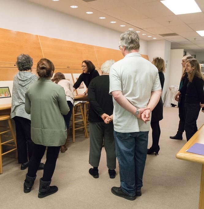 People gathered in a room watching a woman talking.