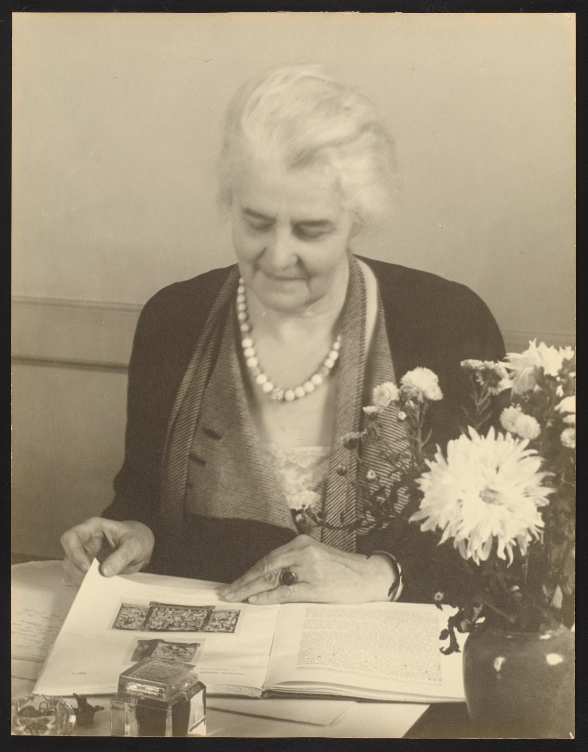 An older woman looks down on an album.