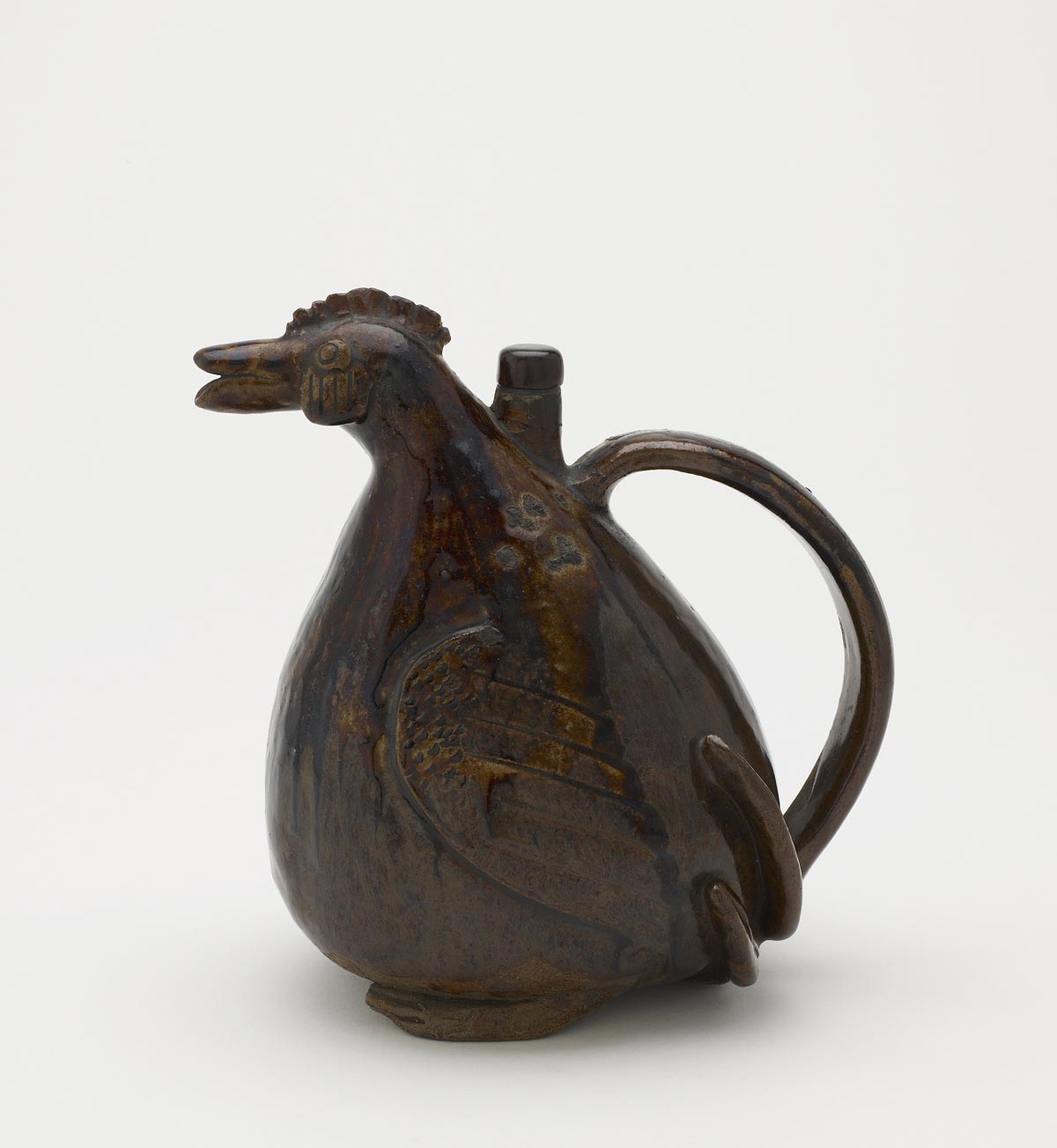 a dark colored vessel in the shape of a bird with a small head and a large round belly