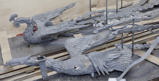 Two metal Phoenix sculptures positioned with their wings in the air placed on cargo packaging.