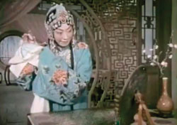 A woman standing at a table in wearing blue robes.