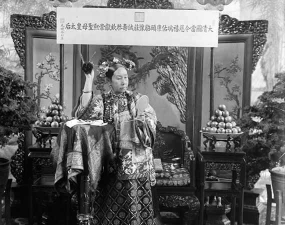 A woman standing wearing a headpiece and extravagant robes.