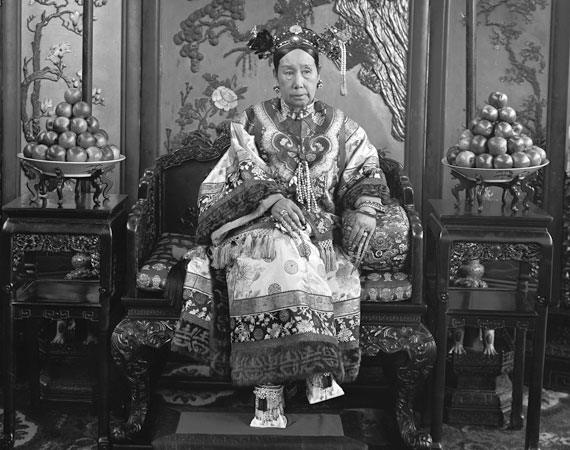 Cixi with carefully stacked mounds of fruit on dishes on either side of her.