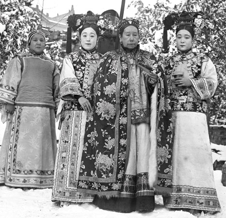 Cixi surrounded by the photographer’s sisters, Deling and Rongling in long robes. Behind them is their mother, Madame Yugeng.