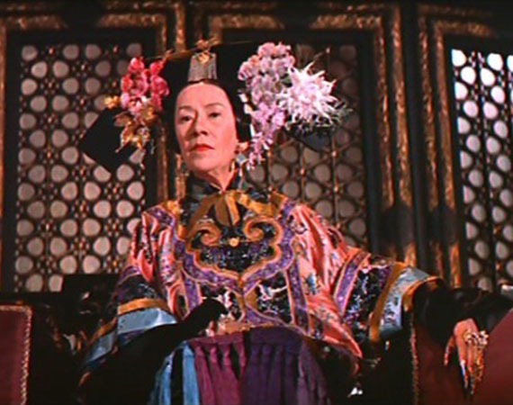 A woman in colorful dress and large headdress with flowers.