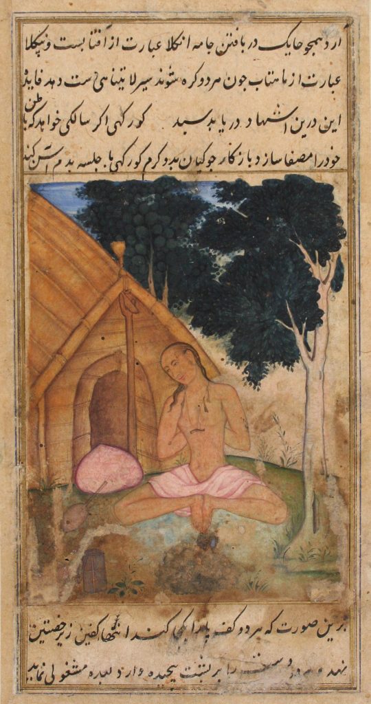 Man sitting in front of a hut with the soles of both feet together and his hands behind his back.