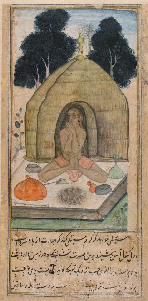 Man sitting cross-legged in front of a hut 