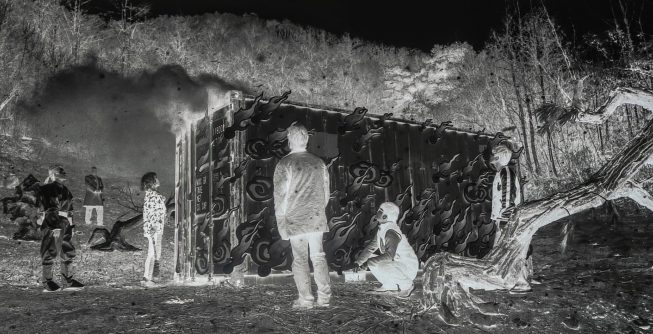 A high-contrast, black-and-white, surreal image of various people scattered around a shipping container in the woods in a smoky scene with jarring, sometimes inverted, tones.