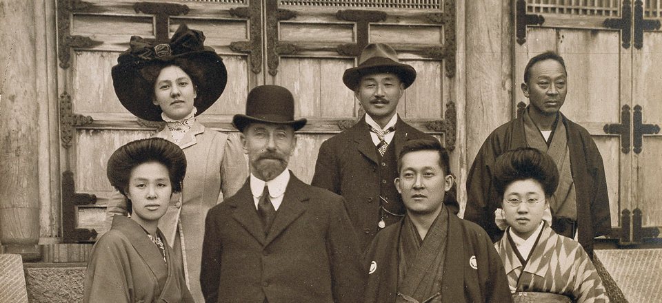 Portrait of a group of people including Freer dressed in a hat, suit, and tie. 