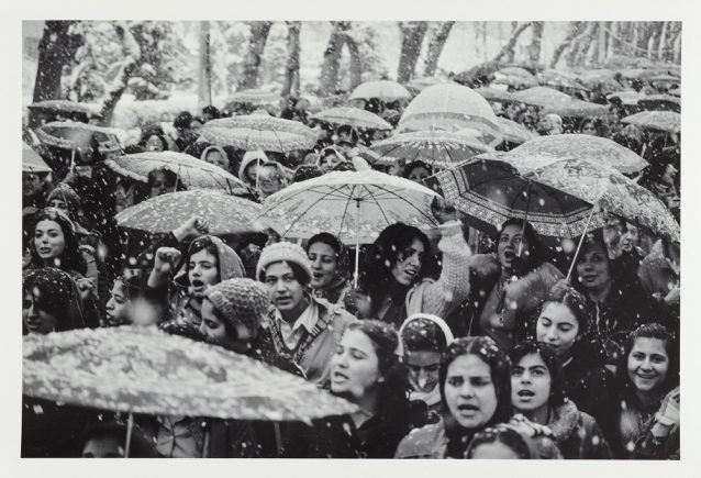 Crowd of women at a street protest, holding umbrellas as it snows