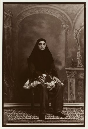 Seated woman wearing a black head covering