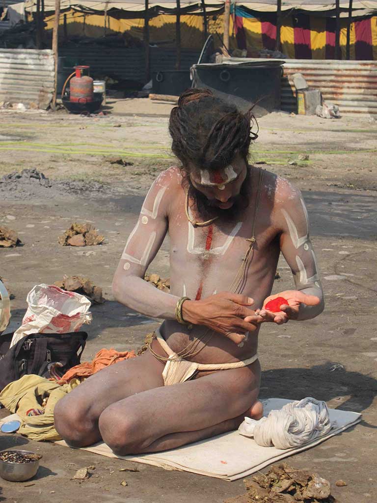 a man painting his body with red ashes