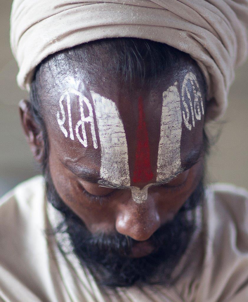 man with red and white symbols written on his forehead