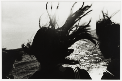 black and white photograph of 3 people with windblown hair on the water