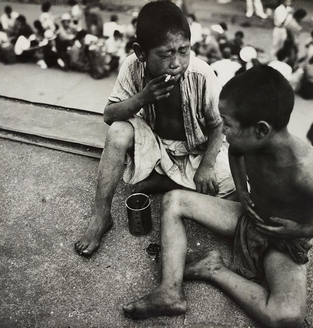 Black and white photo of two children sitting and smoking