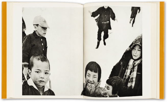 sample spread from Warabegoyomi photobook showing two pages of a book, a black and white photograph across both pages, with several chilren, one laughing, the others looking on