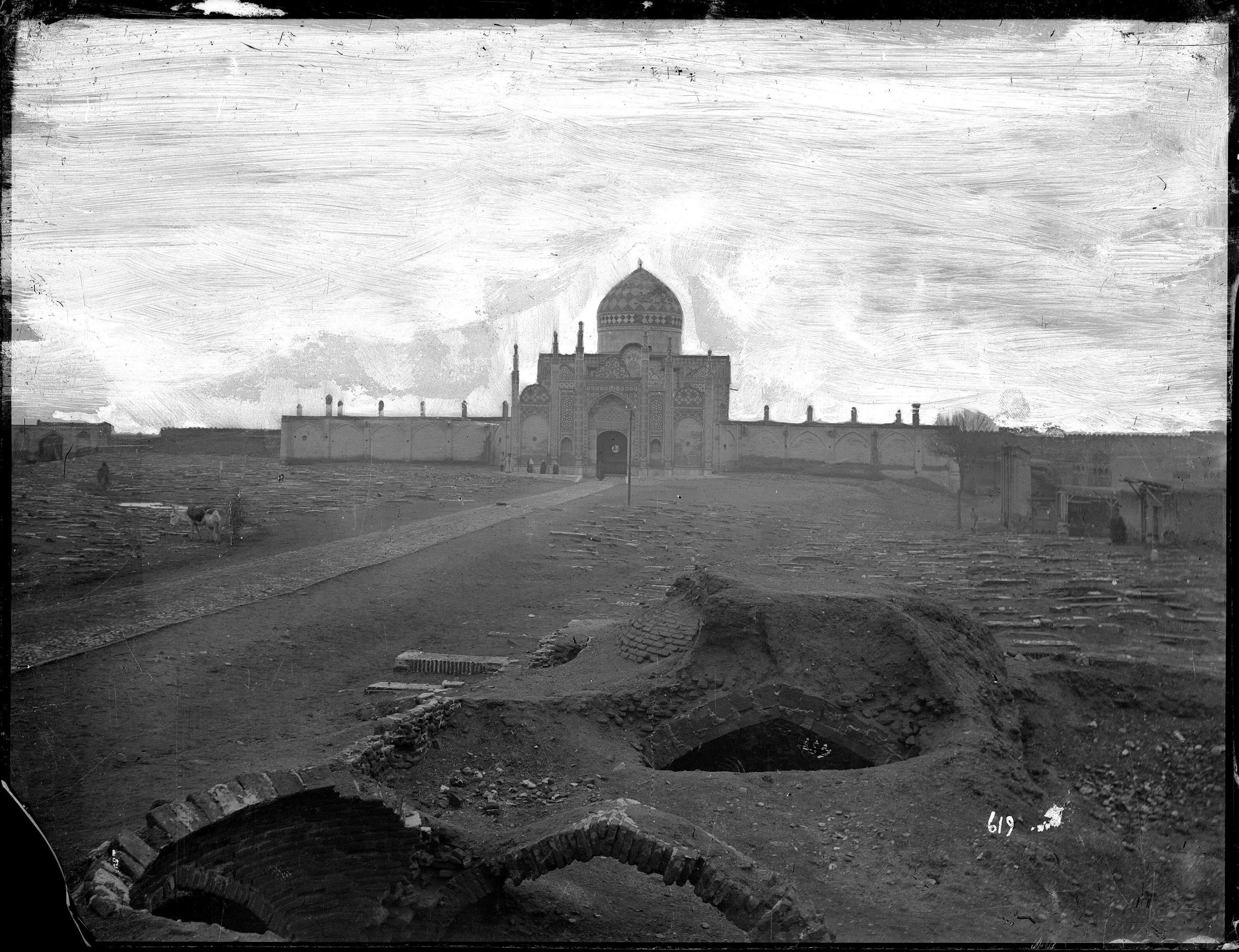 Grayscale photo of a tomb complex with mosque in the distance. The sky is whited out with visible brushstrokes.