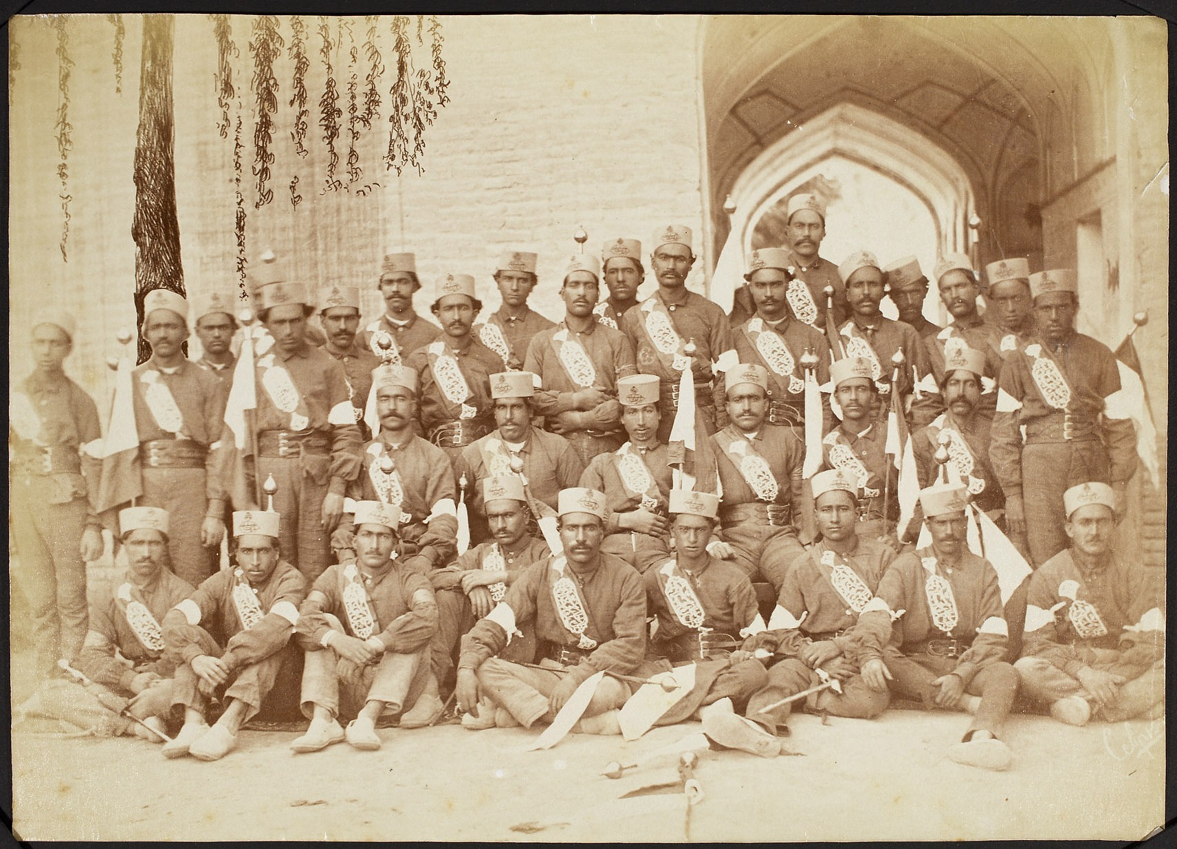 A group photo of a large group of soldiers posing in front of the archway of a building.