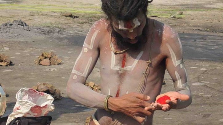 a man painting his body with red ashes