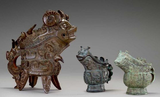 Three metal, handled vessels with zoomorphic designs.