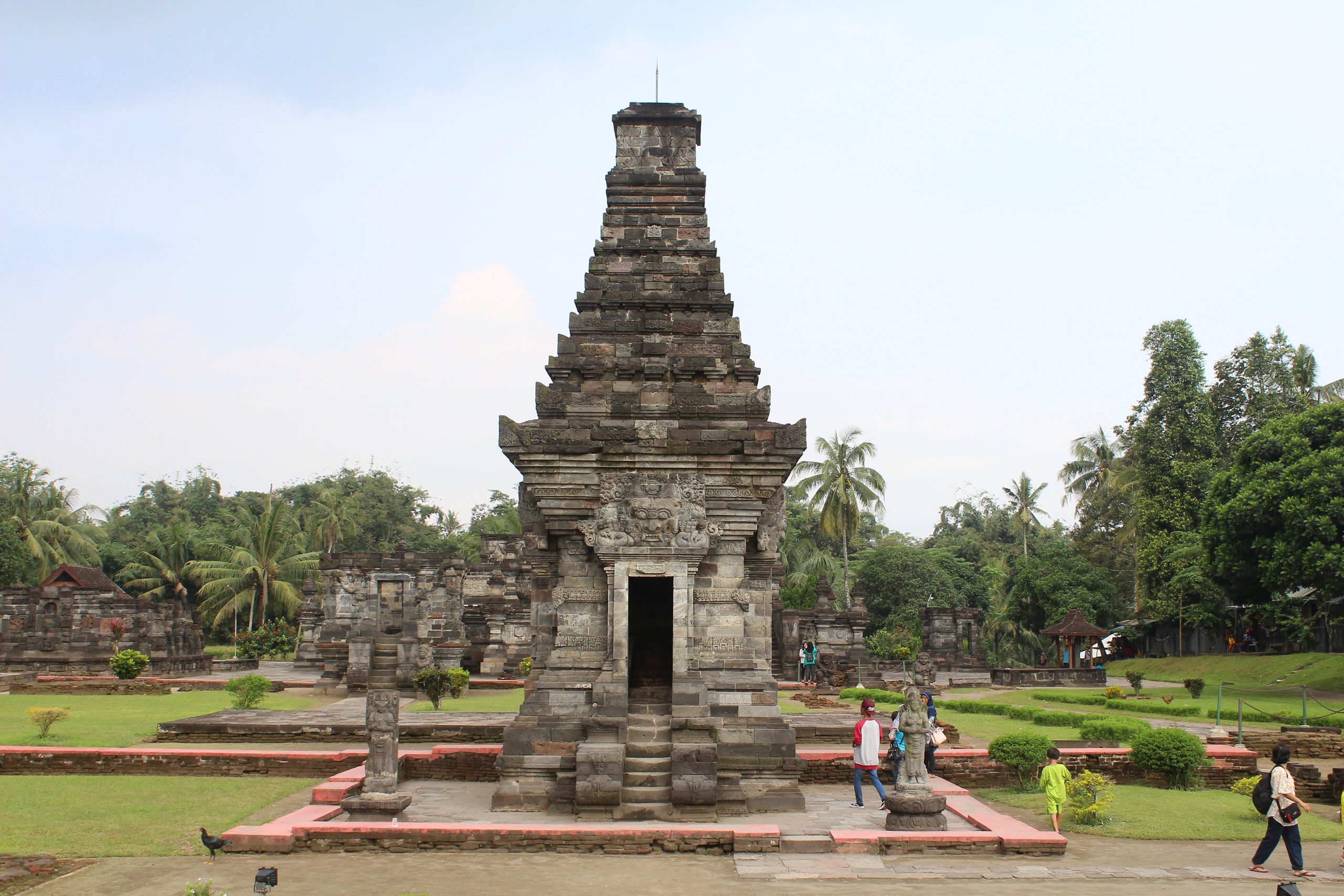 Tall stone temple with demon face over door, in a larger complex