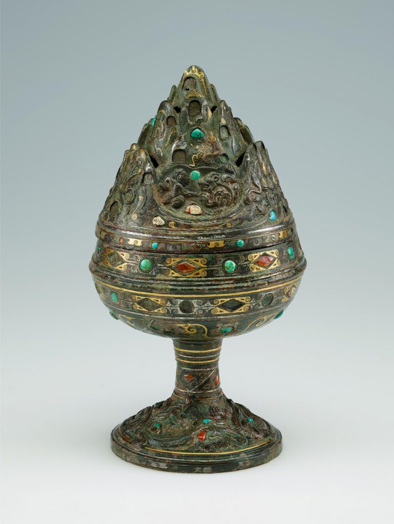 A metal incense burner, studded with jewels, shaped into the form of a mountain.