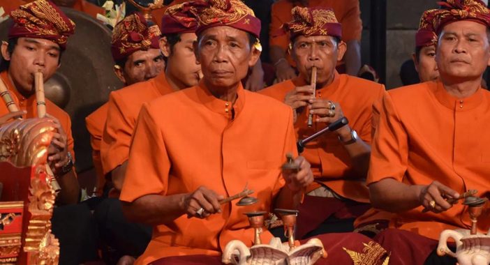 Traditional Indonesian performers dressed in orange, playing instruments