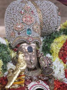 Figure 1. A metal sculpture surrounded in flowers and jeweled decorations including a pearl and jewel covered headpiece.