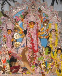 A multi-armed goddess surrounded by other figures, decorated and garlanded