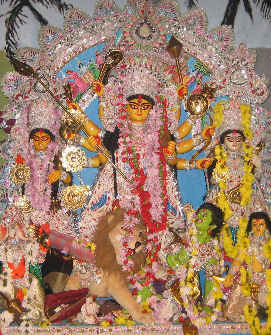 A multi-armed goddess surrounded by other figures, decorated and garlanded