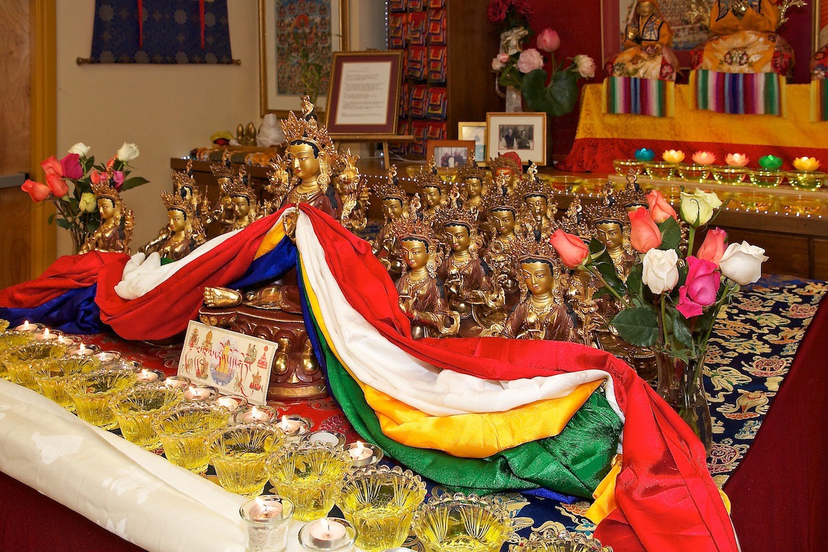 Figure 5. A table covered with brocaded cloth, 5 rows of god, crowned sculptures and one larger sculpture, flowers, glass cups and candles.