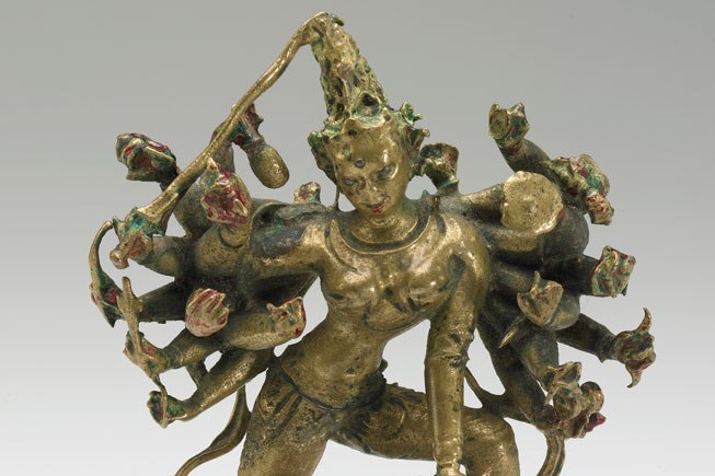 Brass sculpture of Durga, shown in her eighteen-armed form, holds symbols of power and divinity, including a bow and arrow, a sword, a shield, and a drum.