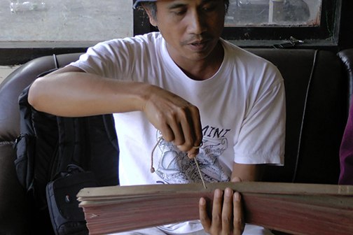 Man holding lontar manuscript.