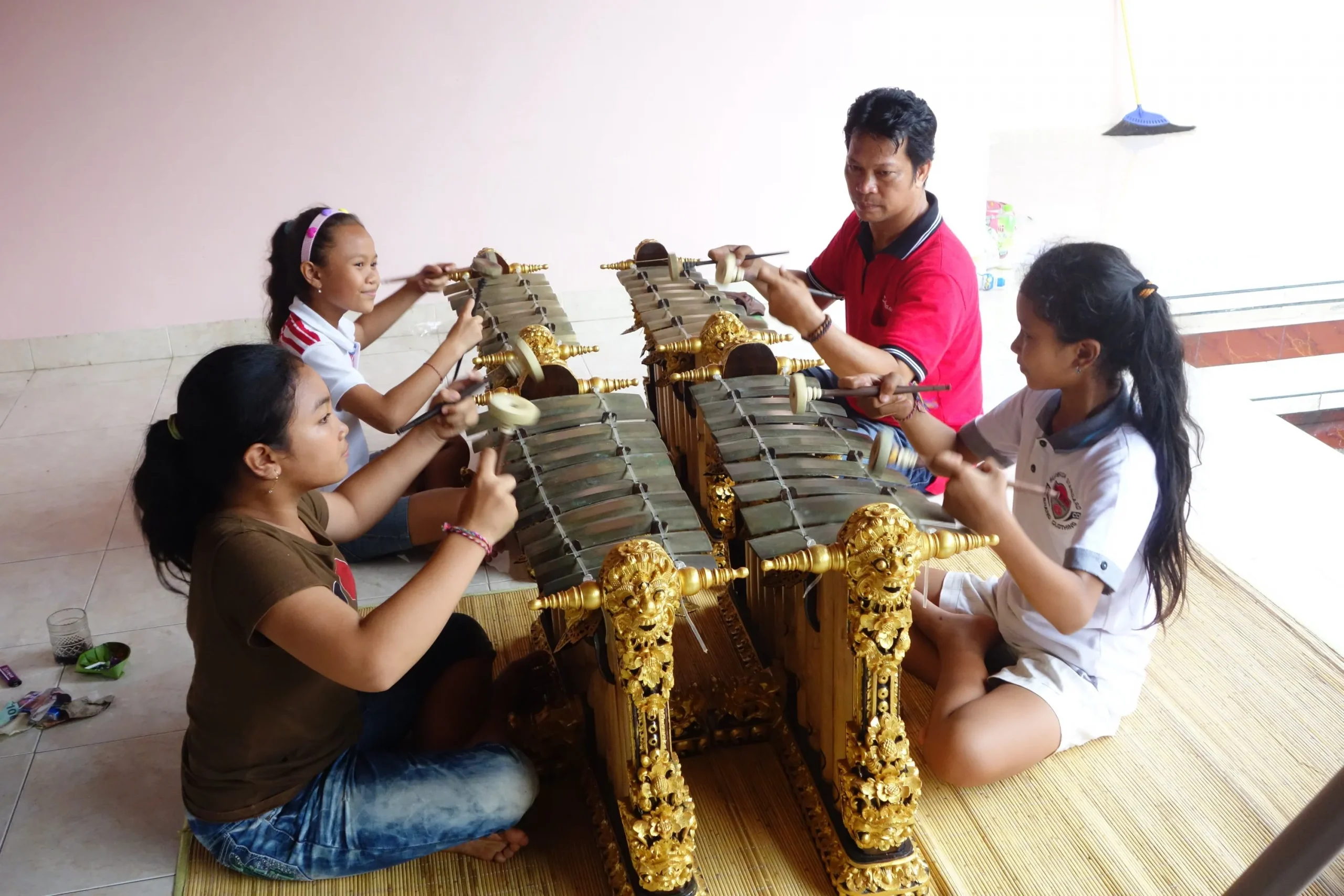 A man playing gender bells with three students.