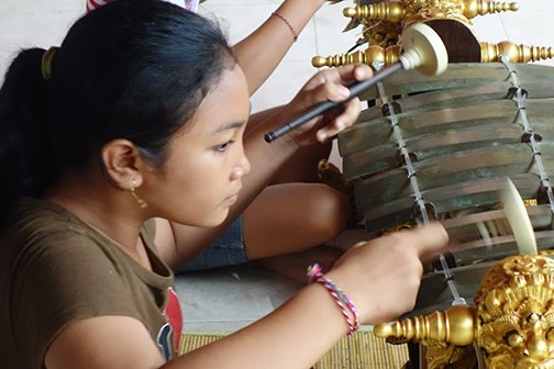 Close-up of a girl playing gender bells, in profile.